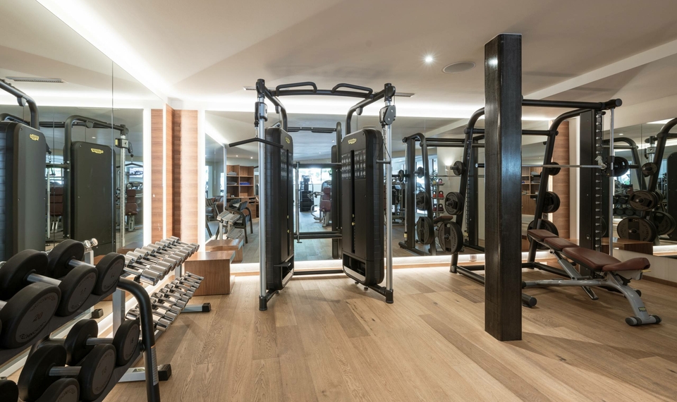 Ein moderner Fitnessraum mit Kraftgeräten, Hanteln und Trainingsbereich im Feldhof in Naturns.