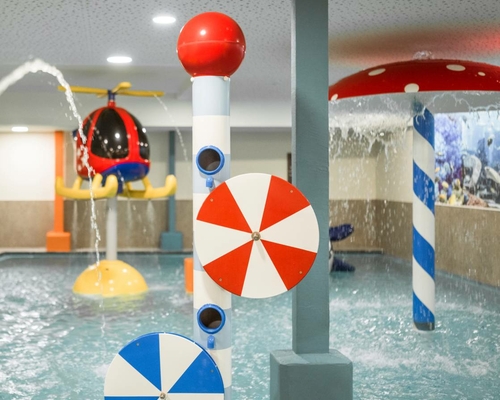 Ein bunter Wasserspielbereich für Kinder mit Fontänen und kleinen Spritzelementen im Indoor-Pool.