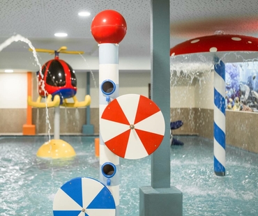 Ein bunter Wasserspielbereich für Kinder mit Fontänen und kleinen Spritzelementen im Indoor-Pool.