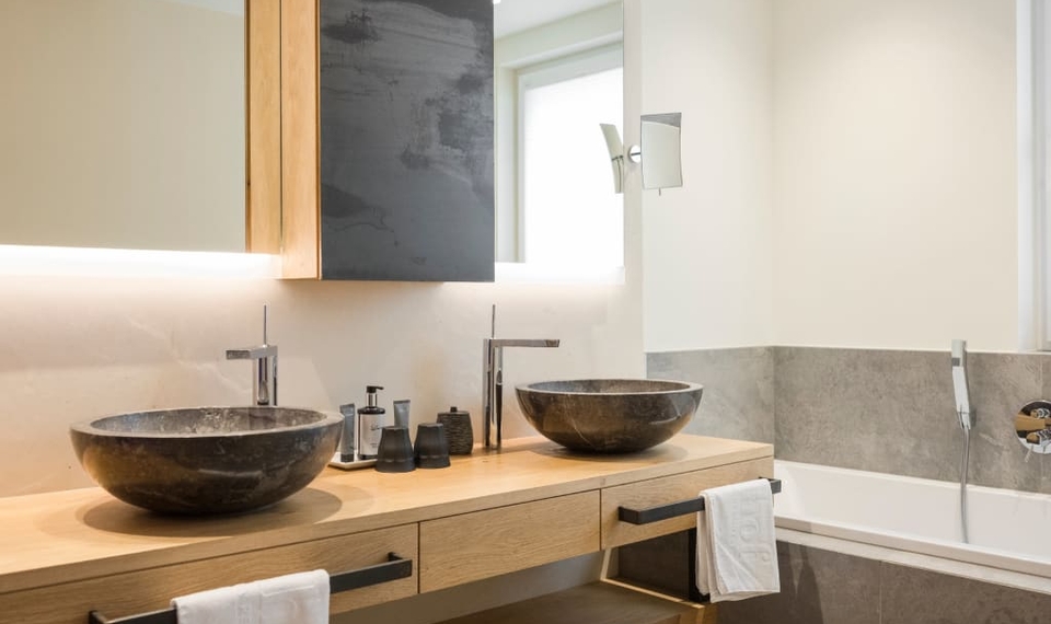 Ein modernes Badezimmer mit Doppelwaschtisch, Badewanne und hellem Holz im Doppelzimmer Blumenwiese.