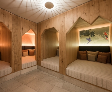 Ruhebereich mit Holzliegen im Feldhof DolceVita Resort Ein gemütlicher Ruhebereich mit Holzverkleidung und gepolsterten Liegen in mehreren Nischen.