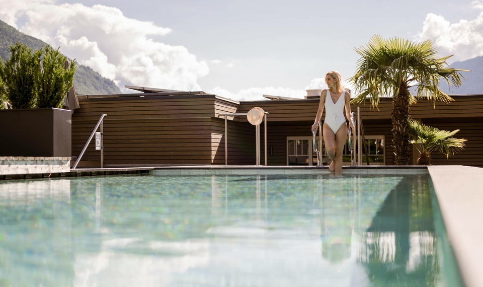 Una donna entra nello Sky Infinity Pool accanto al bordo vasca con vista sulle montagne.