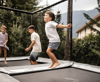 Kinder auf dem Trampolin im Hotelgarten Drei Kinder springen auf einem Trampolin im Garten des Resorts.