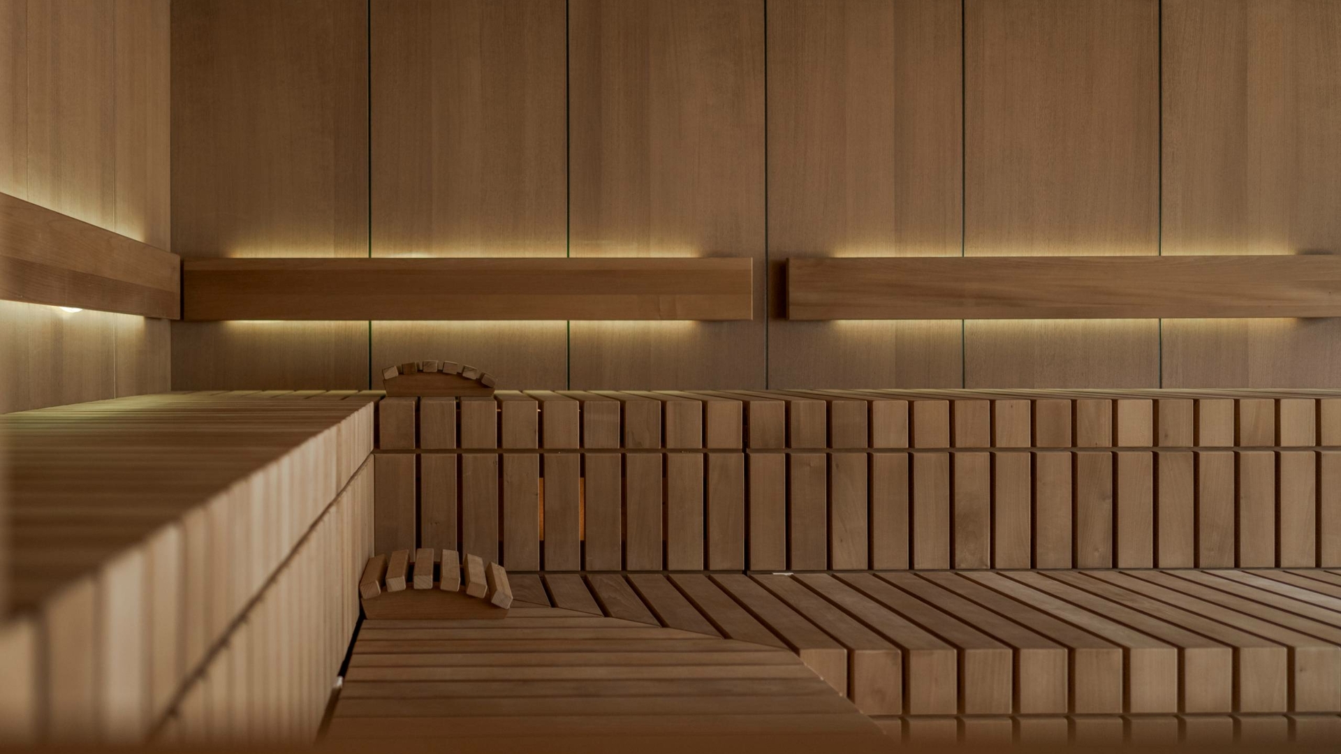 A warm wooden sauna with bench seating and subtle lighting in the Feldhof in Naturns.