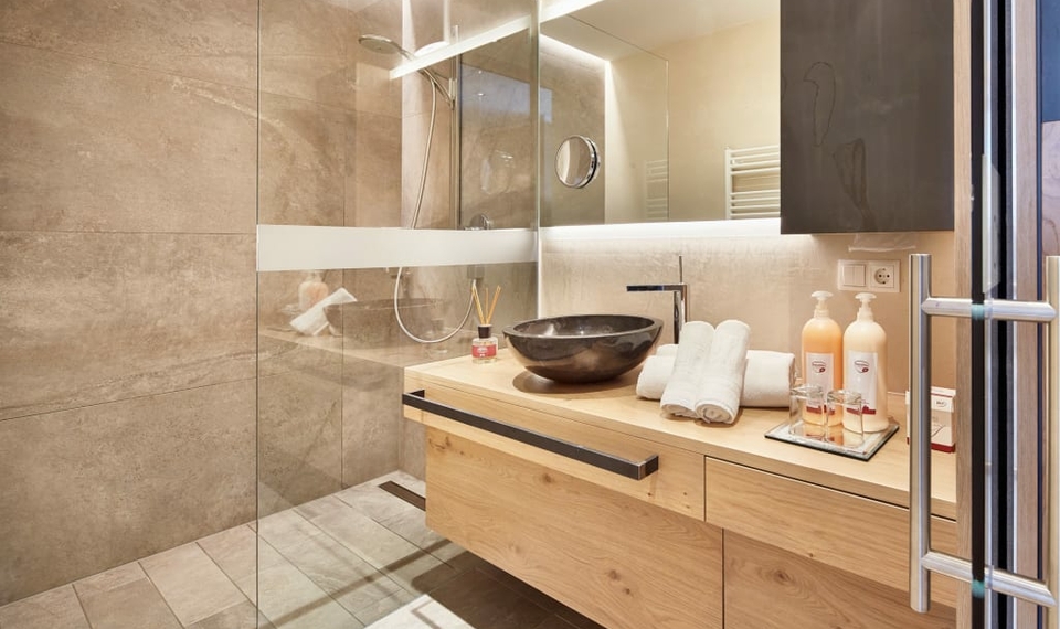 Badezimmer im Chalet Feldhof mit Glasdusche Ein modernes Badezimmer mit Glasdusche, Holzwaschtisch und schwarzem Aufsatzwaschbecken im Chalet.