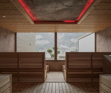 A wooden sauna with benches and a large window overlooking the mountains.