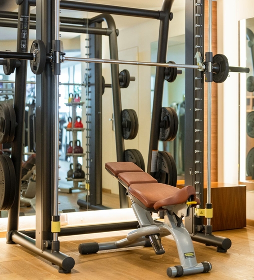 Ein Trainingsbereich mit Hantelbank, Langhantel und Kraftstation im Fitnessraum.