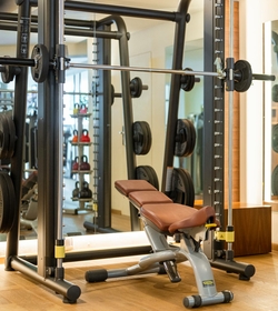 Ein Trainingsbereich mit Hantelbank, Langhantel und Kraftstation im Fitnessraum.