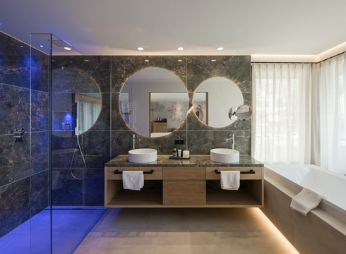 Bagno della Panorama Suite al Feldhof Resort Bagno moderno della Panorama Suite con doppio lavabo, ampia doccia e vasca accanto alla finestra.