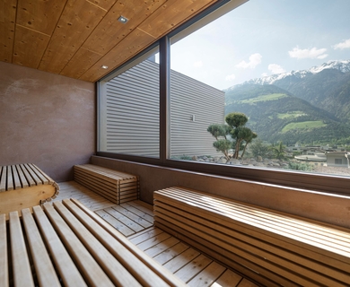 Sauna mit Bergblick im Feldhof DolceVita Resort Eine Holzsauna mit großen Panoramafenstern und Blick auf die Berge im Feldhof DolceVita Resort.