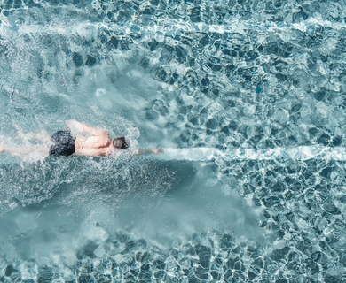 Schwimmer im Pool des Feldhof DolceVita Resort Ein Schwimmer zieht seine Bahnen im türkis schimmernden Poolwasser.