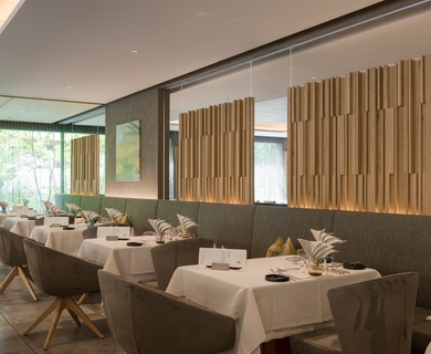 Hotelrestaurant im Feldhof DolceVita Resort Ein elegant gedeckter Restaurantbereich mit Tischen, Polsterstühlen und Holzlamellen im Feldhof DolceVita Resort.