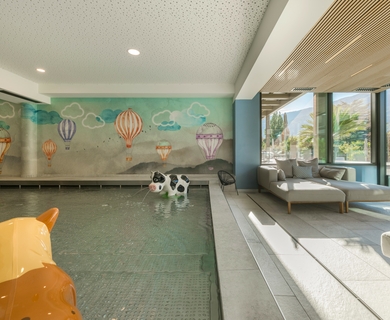 Family Spa mit Kinderpool im Feldhof Resort Ein Indoor-Kinderpool mit Spieltieren und Sitzbereich am Fenster im Feldhof DolceVita Resort.