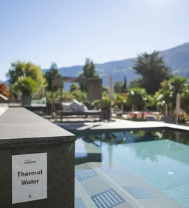 Una piscina con cartello “Thermal Water” e vista sulle montagne nell’area esterna.