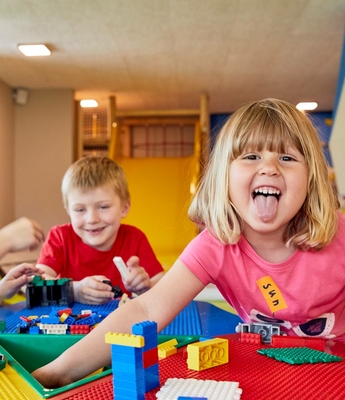 Kinderbetreuung mit Bauklötzen im Feldhof Ein Mädchen und ein Junge spielen mit Bauklötzen an einem Tisch im Kinderbereich.