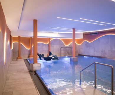 Innenpool im Wellnesshotel Feldhof in Naturns Ein Innenpool mit Beleuchtung und Liegen im Wellnessbereich des Resorts.
