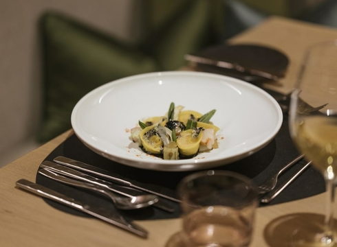Piatto gourmet nel ristorante dell’hotel a Naturno Un piatto gourmet impiattato con cura è servito su un tavolo apparecchiato con posate e bicchiere.