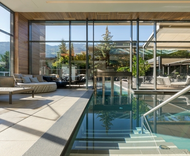 Innenpool im Wellnesshotel Feldhof in Naturns Ein Innenpool mit Liegen und großen Glasfronten im Wellnessbereich des Feldhof DolceVita Resort.