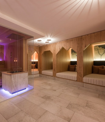 Sauna und Ruheraum im Family Spa Ein Holzsauna-Bereich mit violetter Beleuchtung und gepolsterten Ruhezonen in einem Wellnessbereich.