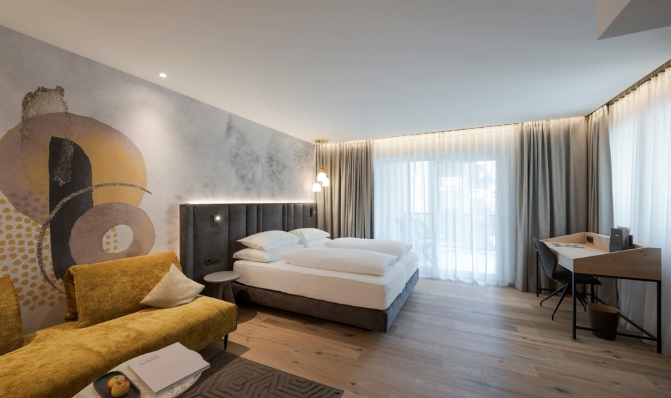 Doppelzimmer La Vita im Feldhof in Naturns Ein großzügiges Doppelzimmer mit Kuschelecke, Schreibtisch und heller Fensterfront.