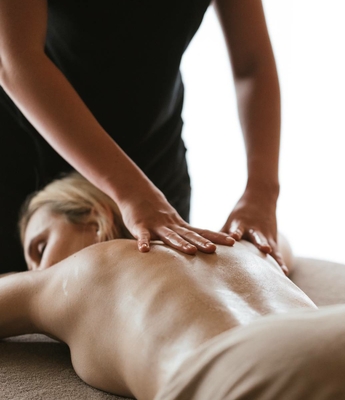 Massage im Spa des Feldhof in Naturns Eine Masseurin behandelt den Rücken einer liegenden Frau im Spa.