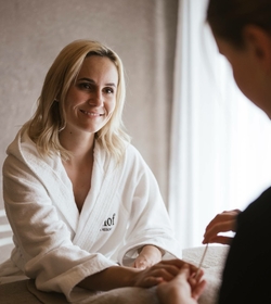 Eine Frau im Bademantel lächelt während einer Massagebehandlung im Spa.