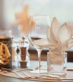 Ein elegant gedeckter Tisch mit Weinglas, Besteck und gefalteter Serviette im Hotelrestaurant.