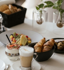 Ein Frühstückstisch mit Croissants, Joghurt, Obst und Kaffee im Feldhof DolceVita Resort.
