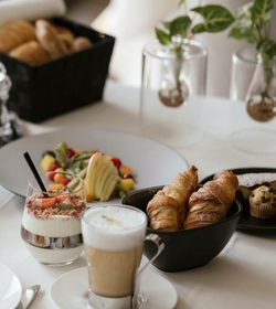 Ein Frühstückstisch mit Croissants, Joghurt, Obst und Kaffee im Feldhof DolceVita Resort.