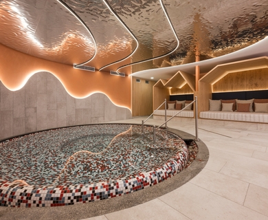 Wellnessbereich mit Ruhebecken im Feldhof Ein ruhiger Wellnessbereich mit rundem Ruhebecken, Liegefläche und warm beleuchteter Holzarchitektur.