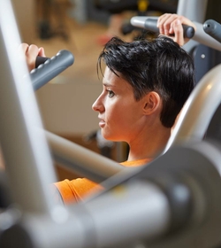 Eine Frau trainiert an einer Krafttrainingsmaschine im Fitnessraum.