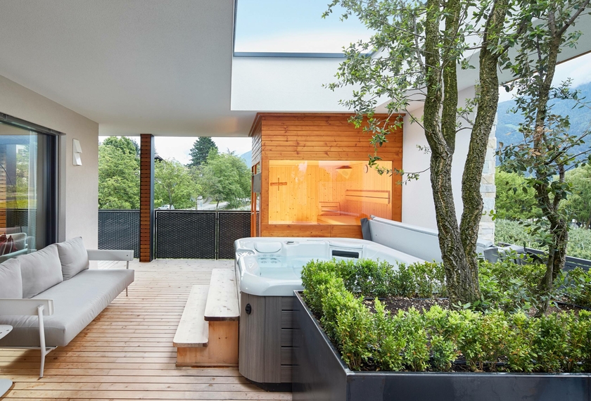 Loggia del chalet con whirlpool e sauna al Feldhof Una loggia del chalet con whirlpool, sauna, panca e vista sul verde.