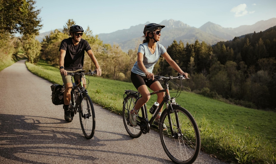 Two cyclists ride along a path through the landscape near Naturns.