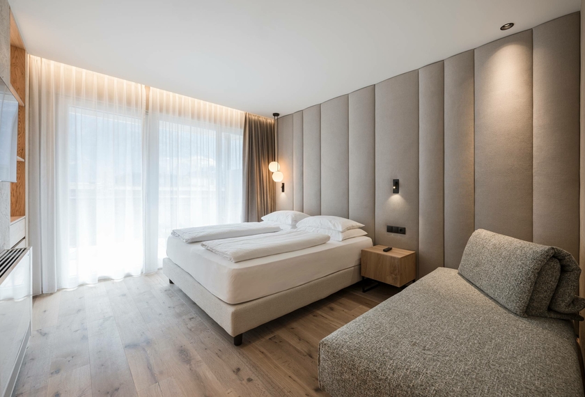 A bright bedroom in the Suite Dolce Vita with a double bed, daybed and floor-to-ceiling window.