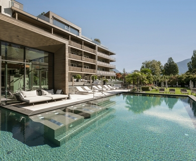 Hotelpool im Feldhof DolceVita Resort Ein großzügiger Hotelpool mit Holzdeck, Liegen und Glasfront am Feldhof DolceVita Resort.