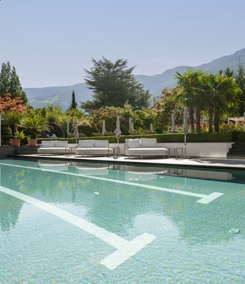 Wellnesspool im Feldhof in Naturns Ein ruhiger Außenpool mit Liegen, Palmen und Bergblick im Wellnessbereich.