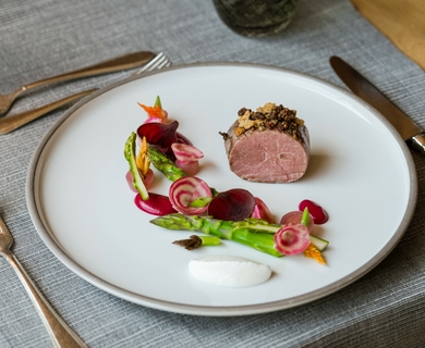 Gourmet-Hauptgang im Hotelrestaurant in Naturns Ein fein angerichteter Gourmet-Hauptgang mit Fleisch, Gemüse und Sauce auf einem weißen Teller.