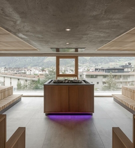 Ein Ruheraum im Sky Spa mit Liegen, Fensterfront und Blick auf den Ort.