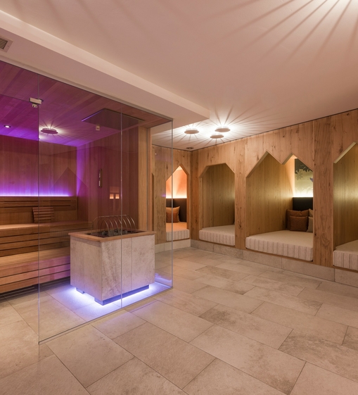Ein moderner Saunabereich mit Holzliegen, warmem Licht und violett beleuchteter Glaswand im Family Spa.
