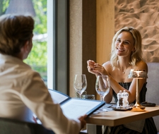 Zwei Gäste sitzen im Restaurant und sprechen bei einem gedeckten Tisch im Wellnesshotel.