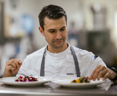 Gourmetküche im Feldhof DolceVita Resort Ein Koch richtet zwei Teller mit fein angerichteten Speisen in der Gourmetküche an.
