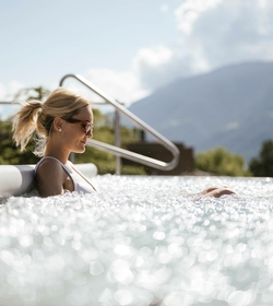 Una donna si rilassa nella Sky Infinity Pool con le montagne sullo sfondo.