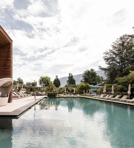 Una piscina all’aperto con lettini e vista sulle montagne in un wellness hotel a Naturno.