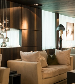Ein moderner Loungebereich mit Sofa, Stehlampe und hängenden Glasleuchten neben großen Fenstern.