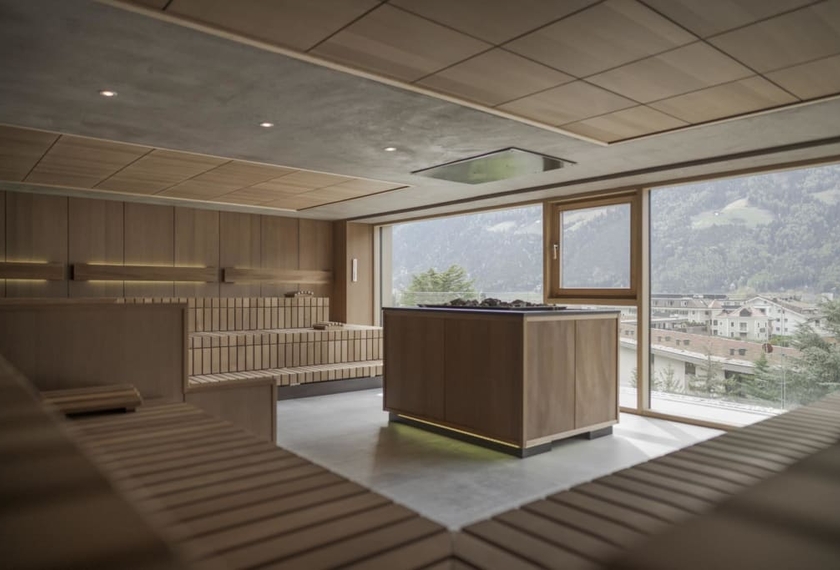 Sauna con vista panoramica al Feldhof Una sauna moderna con panche in legno e vista sulle montagne e sul paese attraverso ampie finestre.