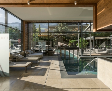 Wellnessbereich mit Innenpool im Feldhof Ein moderner Wellnessbereich mit Innenpool, Liegen und großen Glasfronten öffnet den Blick ins Grüne.