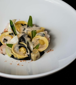 Tortellini mit Garnelen und grünen Blättern auf einem weißen Teller im Hotelrestaurant.