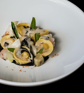 Tortellini mit Garnelen und grünen Blättern auf einem weißen Teller im Hotelrestaurant.