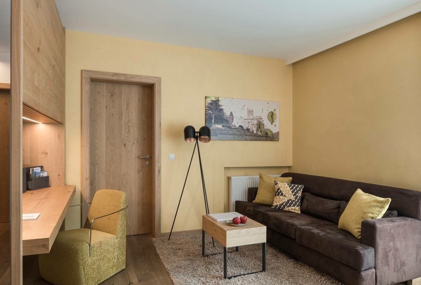 Un accogliente soggiorno di suite con divano, poltrona, tavolino e scrivania.