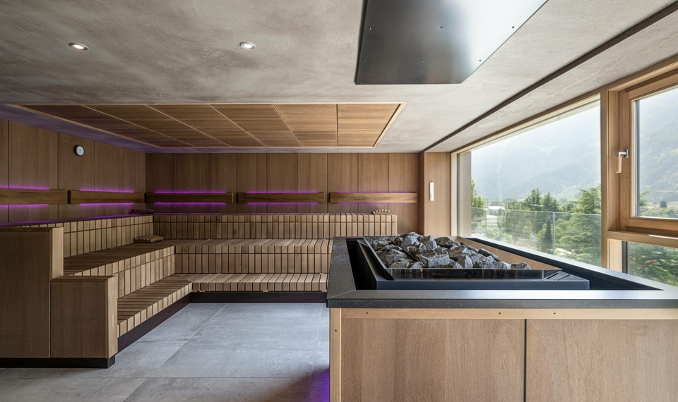 A modern sauna with wood paneling and a mountain view through a large window.